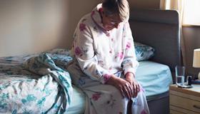 Woman sitting on side of bed