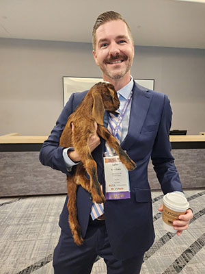 Luke Davis at Creating Health Work Environments holding a small goat.