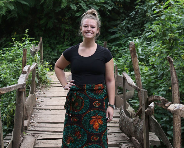 Brooklyn Loxtercamp stands on wooden bridge in a tropical forest.