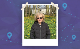 Kathy Black in front of expanse of daffodils with trees and building in the background.