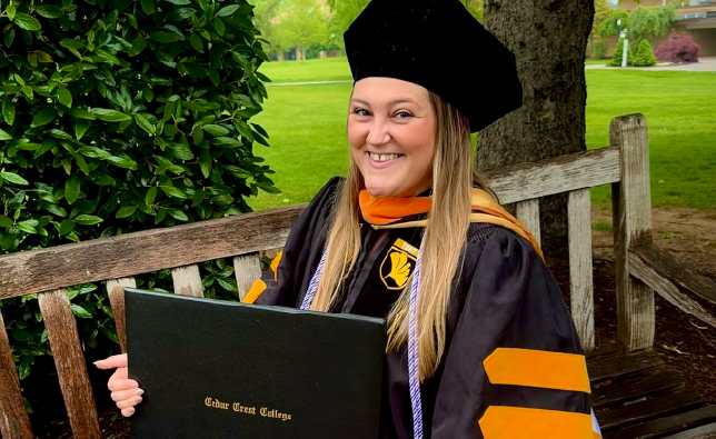 Amanda Howard in her graduation cap and gown holding her diploma.