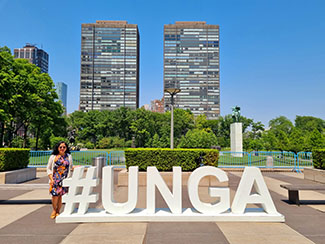 Monina Hernandez outside next to an installation that says #UNGA.