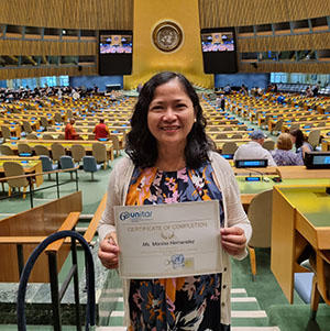 Monina Hernandez inside the UN General Assembly holding her certificate of completion with UNITAR.